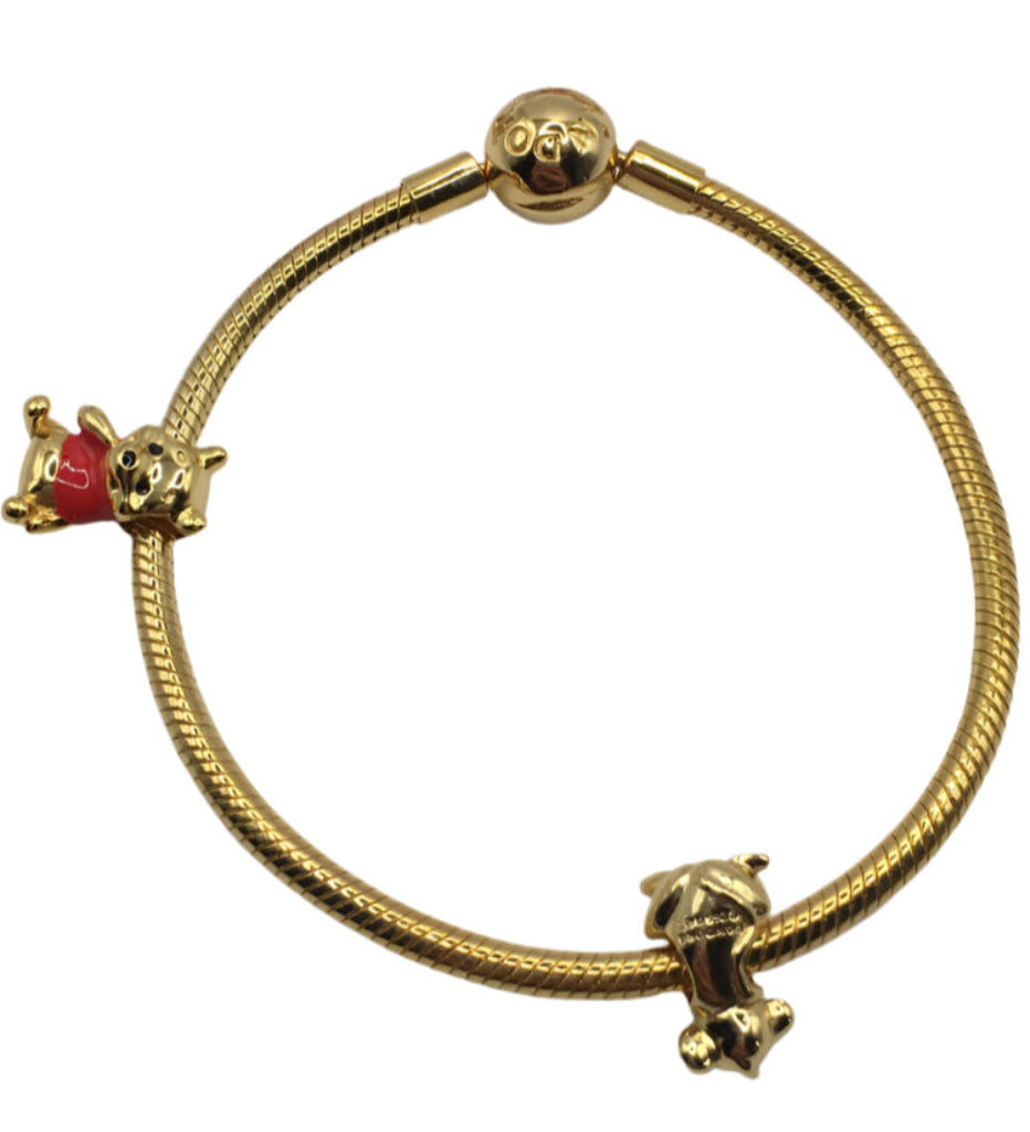 Pandora Gold bracelet with two Disney charms on a white background