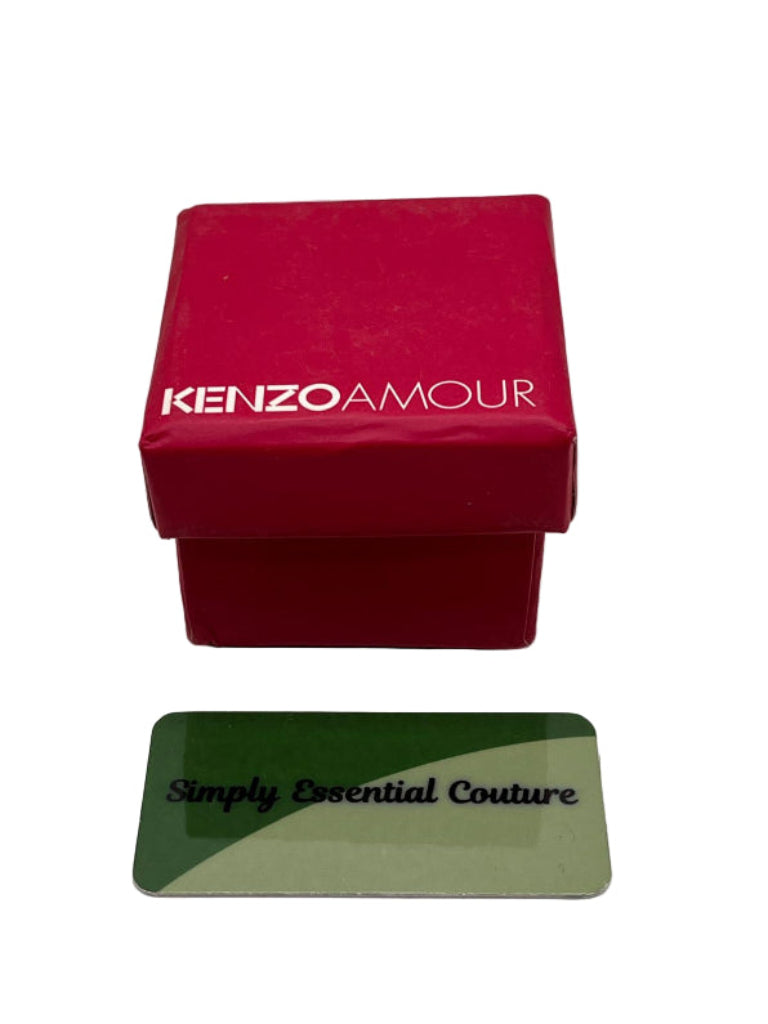 Red 'Kenzo Amour' box with a green card displaying 'Simply Essential Couture' on a white background
