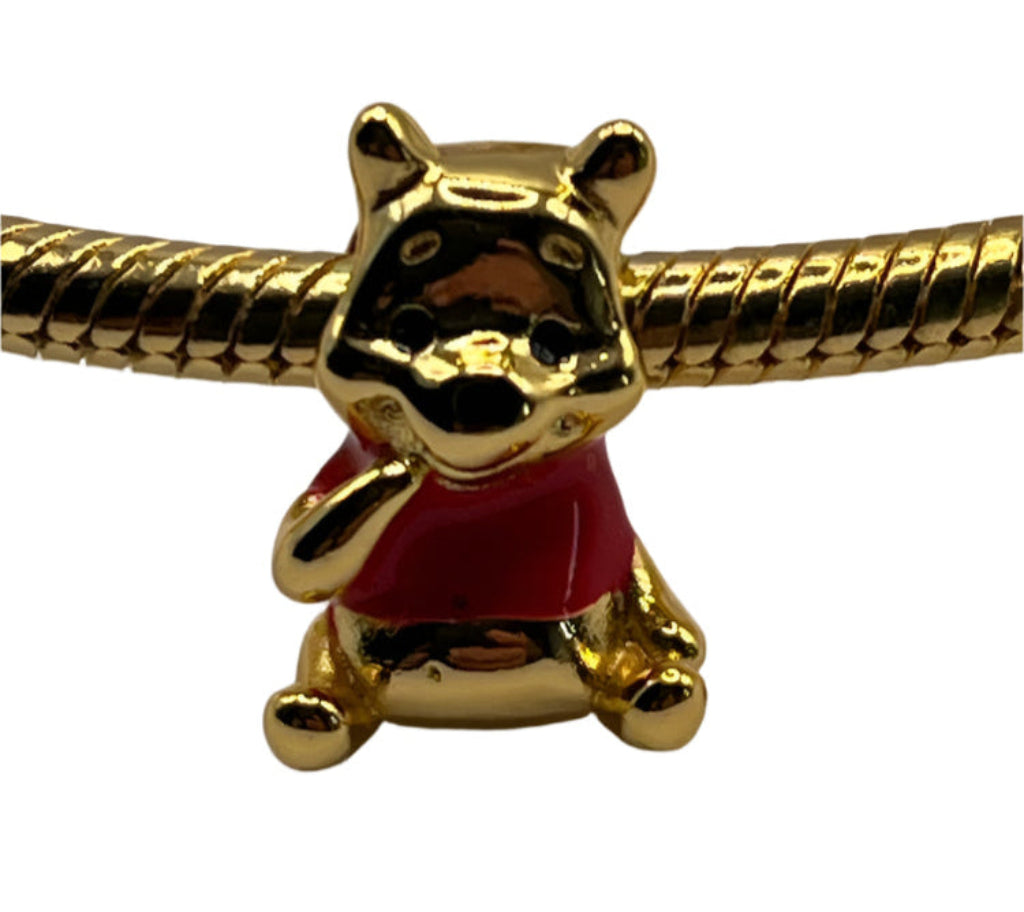 Gold Winnie The Pooh bear charm with red outfit on a white background