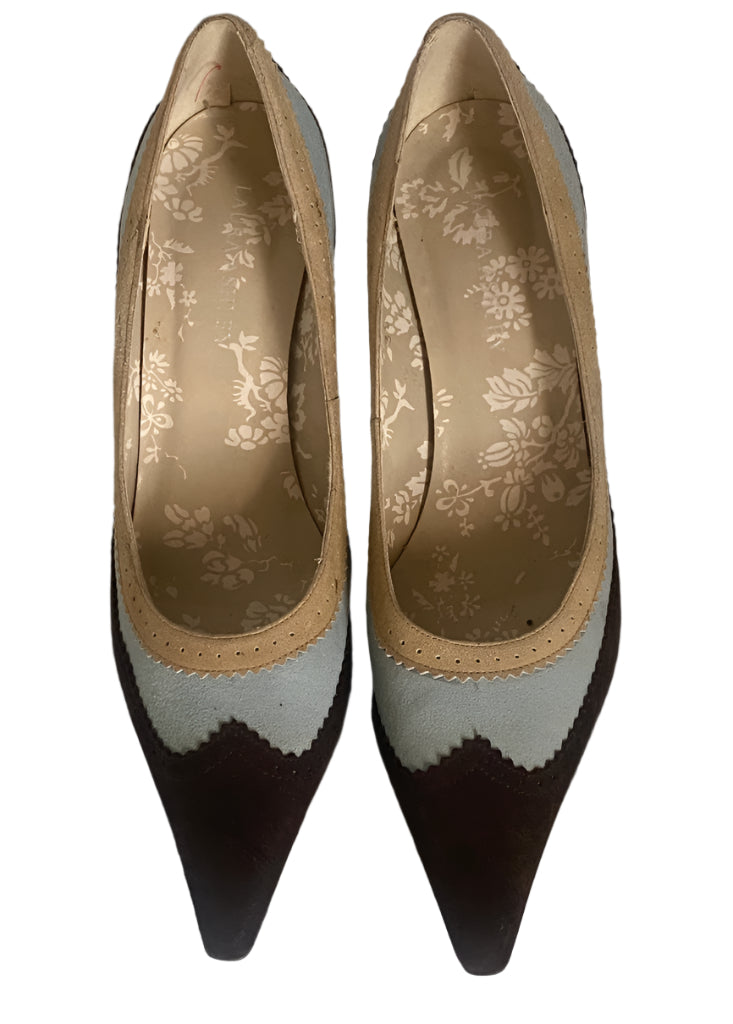 Pair of high-heeled shoes with a floral pattern on the insole, placed on a textured surface.