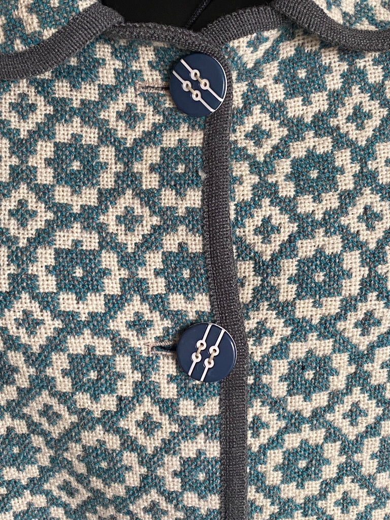 TREFRIW Close-up of a textured fabric with a geometric pattern and a button on a garment.