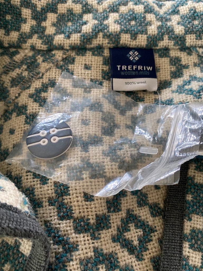 Button with packaging on a patterned fabric background, featuring the TreFriw brand.