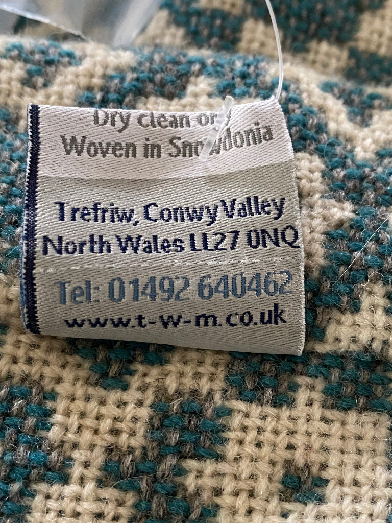 Textile label on a checkered fabric background with text and contact information.