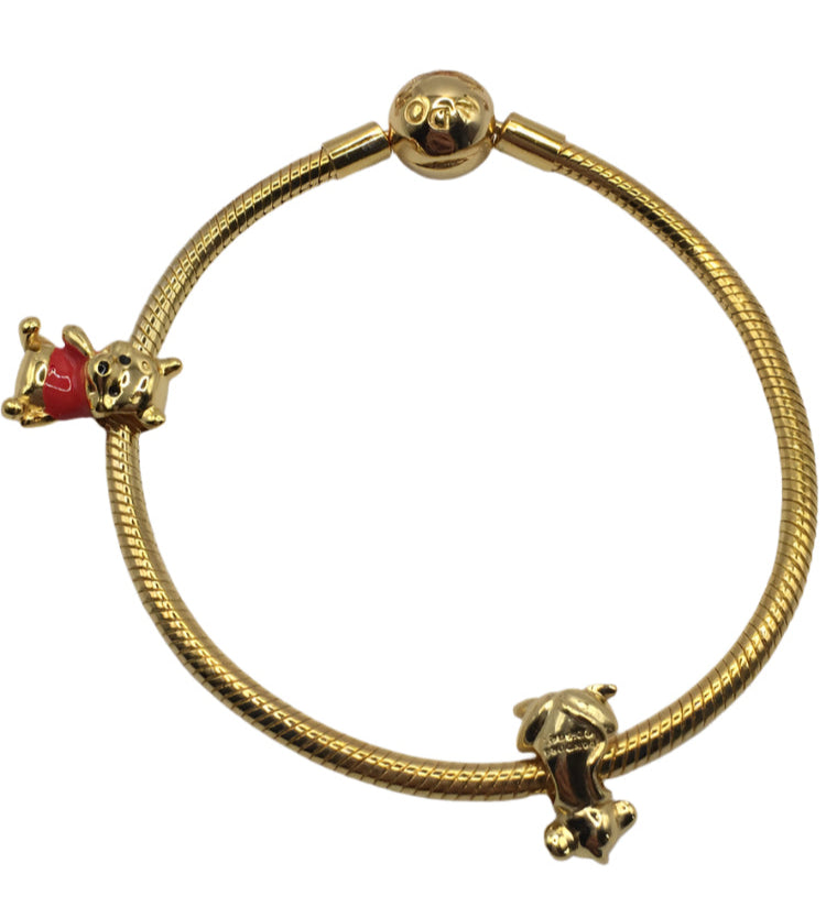 Gold bracelet with two charms on a white background