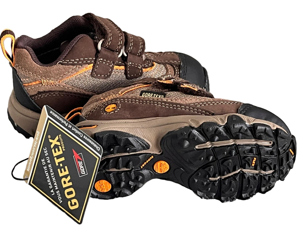 Brown hiking boots with GORE-TEX label on a striped fabric background
