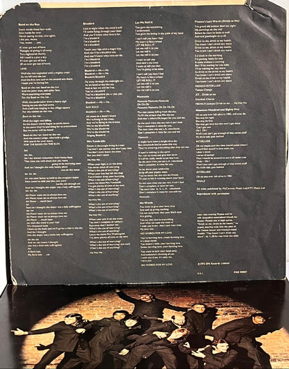 Back cover of a vinyl record with text and a band photo. Wings - Band On The Run