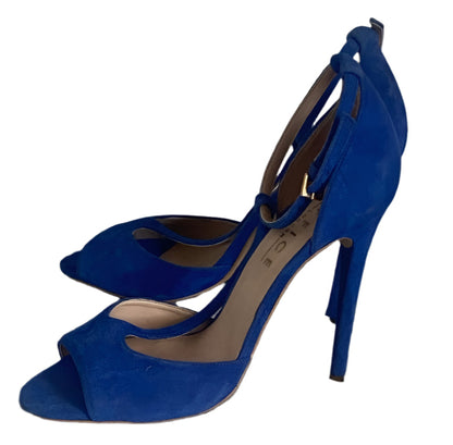 Blue high-heeled shoes on a textured surface with a neutral background