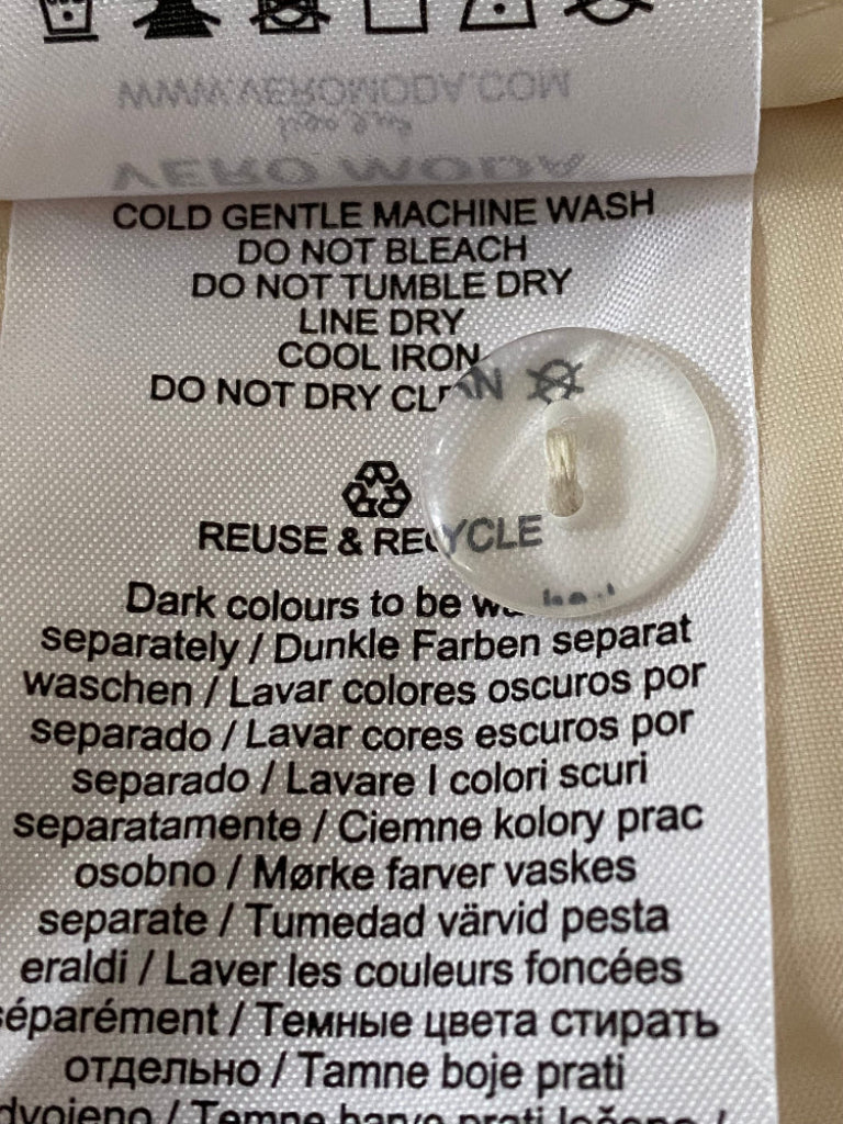Clothing label with washing instructions and recycling symbol on a beige fabric background