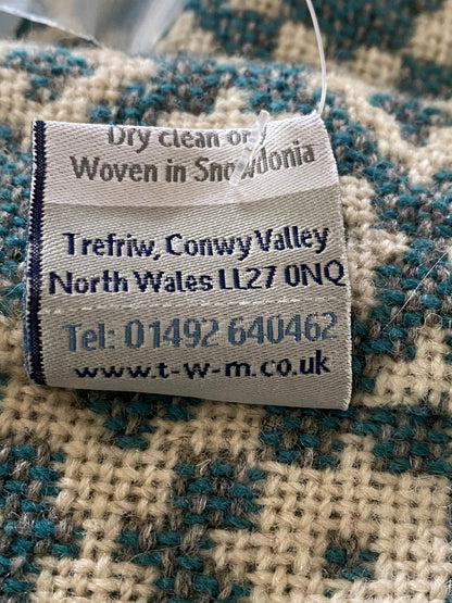 Textile label on a checkered fabric background with text and contact information.