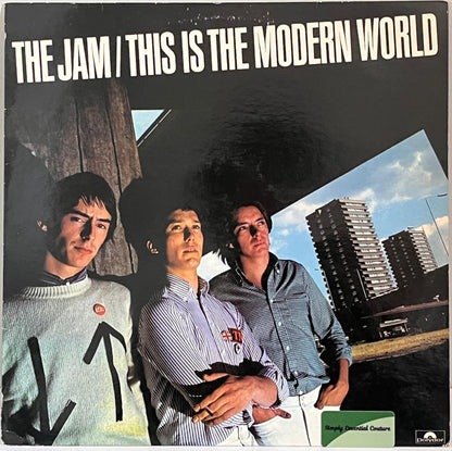Vinyl record cover for 'This is the Modern World' by The Jam with three band members and cityscape.