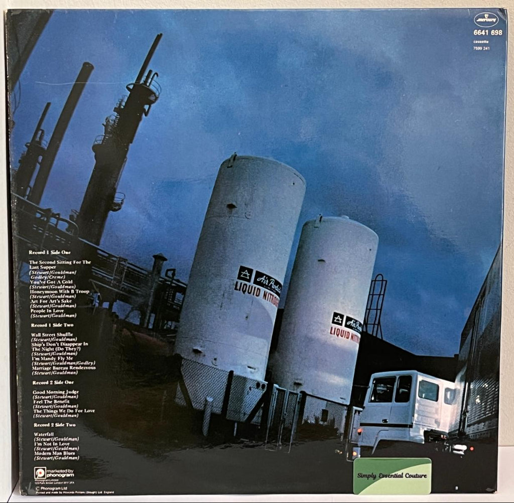 10CC - Album cover with industrial imagery of tanks and a truck against a blue sky.